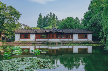 Traditional Chinese house by pond with reflection in water, in a Chinese garden, near West Lake, Hangzhou, China