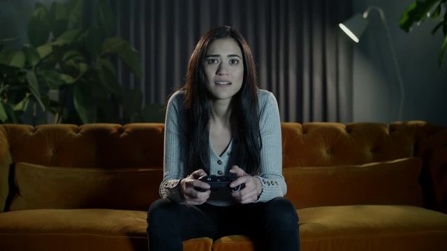 Emotional gamer girl playing at home feeling the extreme highs and lows of an exciting and intense video game.