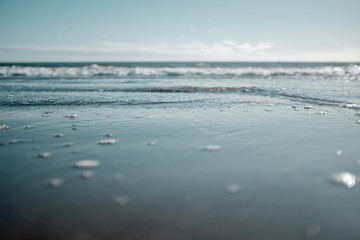 Ground level view of a wave receding back into the ocean on a sandy beach