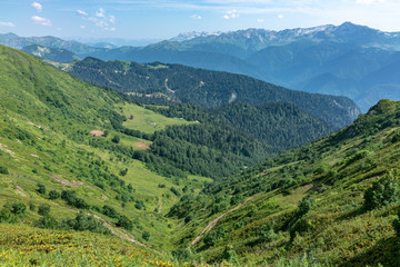 View over the Green Valley, surrounded by mountains vyskokimi on a clear summer day. Krasnaya Polyana, Sochi, Caucasus, Russia.