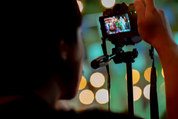 Blurred motion picture of man using the camera with tripod with sparkling bokeh lights in background