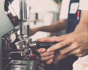 Man barista using coffee machine for making coffee.