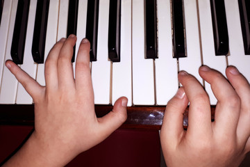  children's hands on the keys of the piano