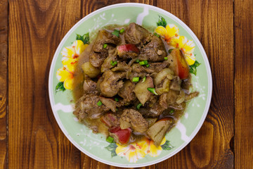 Stewed chicken liver with apple and onion on wooden table