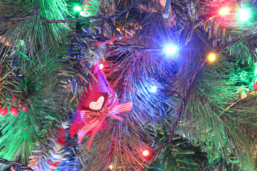 A close view of a green leaves Christmas tree with electric lights decorations and hanging ornaments in a bright colored atmosphere