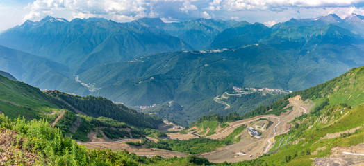 Serpentine road leading to the cable car station. High mountains on the horizon. Krasnaya Polyana, Sochi, Caucasus, Russia.