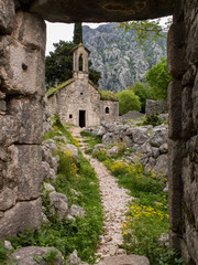 Path leading to an ancient stone church through a stone gate