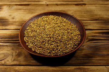 Fenugreek seeds in ceramic plate on wooden table