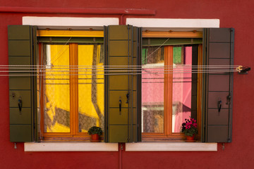 colorful houses reflected in the windows of a colorful house on the island of Burano