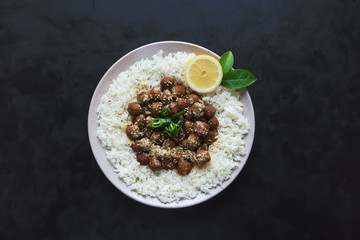 Juicy diet meatballs with rice on a black table.