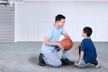 Father teaching his son to play basketball