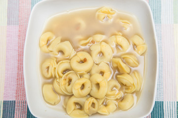 horizontal image with detail with top view of a plate of pasta in hot broth
