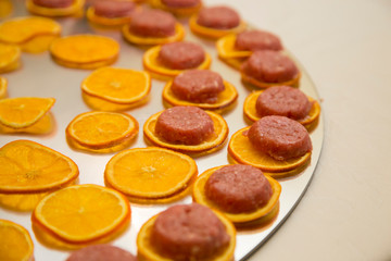 horizontal image with detail of thin slices of orange arranged neatly on a tray prepared for a party