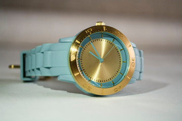 Wrist women watch with the gold dial and a blue rubber thong.