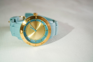 Wrist women watch with the gold dial and a blue rubber thong.