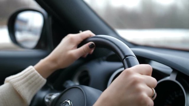 Closeup of female hands. The girl drives a car, turns the steering wheel, the car is in motion 4K Slow Mo