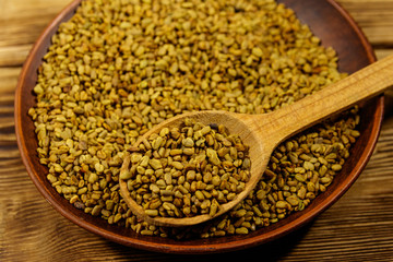 Fenugreek seeds in ceramic plate on wooden table