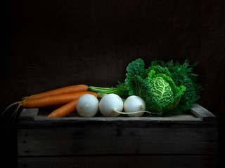 Winter vegetables still life, chiaroscuro Baroque style. Light painting. Cabbage, carrots, turnip.