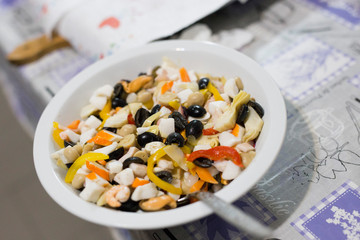 horizontal image with detail of a seafood salad with olives and peppers fish photographed inside a white plate over a table
