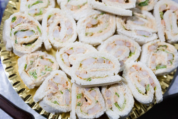 horizontal image with detail of open sandwiches with ham and salmon served on a tray during a party