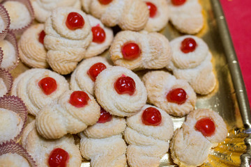 horizontal image with close detail of almond pastries with red cherry served on a tray