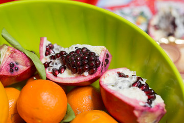 horizontal image with close up detail of an open pomegranate served in a green basket
