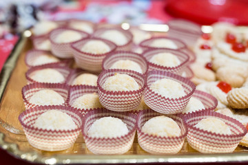 horizontal image with a close-up detail of coconut cakes served on a tray during a party