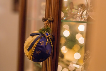 horizontal image with a close-up detail of a Christmas ball re-issued in blue and gold-colored fabric hanging from a knob