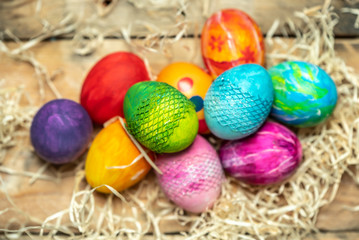 Fototapeta na wymiar beautiful, bright, very colorful hand-painted eggs on a contrasting, raw, natural background from wooden planks