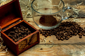 A glass cup with instant coffee next to roasted coffee beans, on a wooden, natural, rustic table