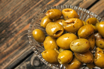 Olives with spices in a crystal bowl on a old wooden table
