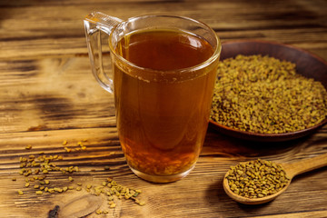 Egyptian yellow tea or Methi Dana drink and fenugreek seeds on wooden table