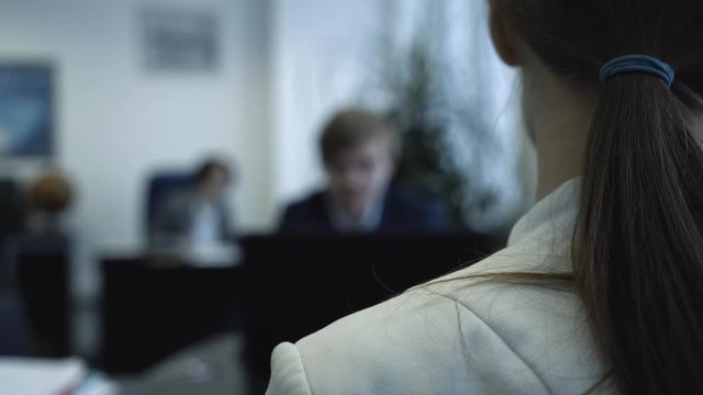 Rear view of female worker in office focusing on screen. Close-up