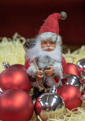 Père Noël assis dans les décorations de noël Fond rouge avec paille