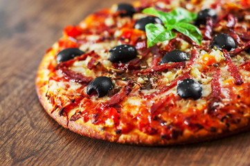 Pizza with Mozzarella cheese, salami, pepper, ham, pepperoni, olives, Spices and Fresh Basil. Italian pizza on wooden background