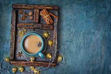 Masala chai tea with milk and spices in vintage wooden box and Christmas lighted garland