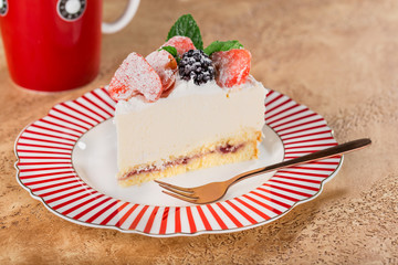 piece of cottage cheese cake with strawberries, blackberries and mint on a beautiful festive plate.