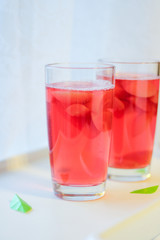 в двух стеклянных стаканах налит розовый свежий напиток (компот, лимонад, коктейль, сок). 