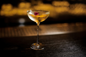 Elegant cocktail glass filled with tasty sweet drink decorated with rose bud