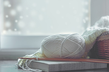 Cozy winter home with warm knitted sweaters and ball of yarn near windowsill, home hobbies, vintage...