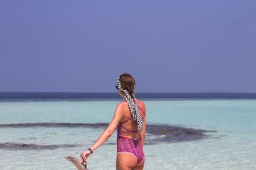 Young blonde girl with a violet swimsuit in a desert island (Ari Atoll, Maldives)