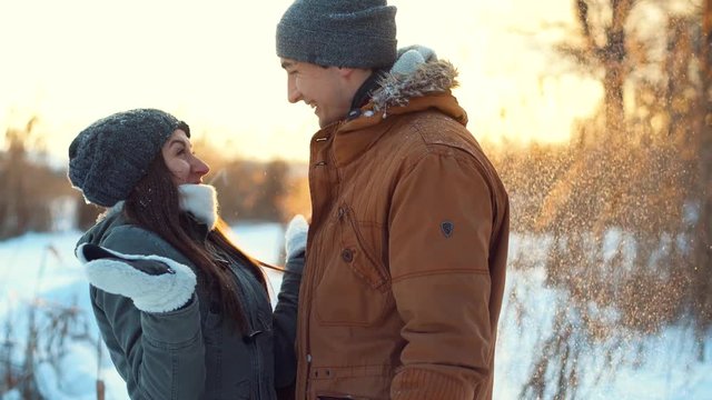 Love story, a boyfriend warming girlfriend hands in winter park.