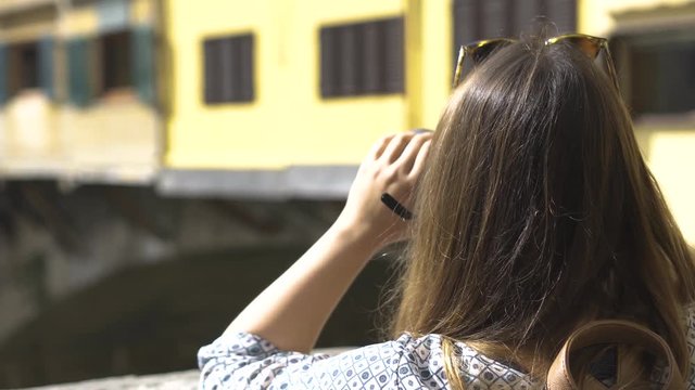 Girl photographer taking pictures of Ponte Vecchio bridge in Florence Italy