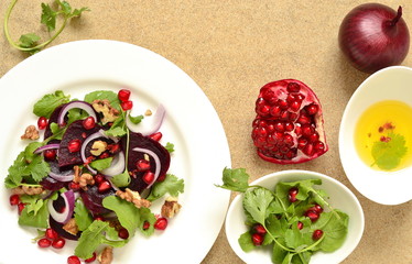 Beetroot salad with arugula, walnuts and pomegranate seeds, top view, copy space