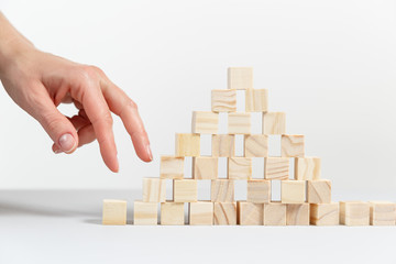 Closeup of businessman making a pyramid with empty wooden cubes.