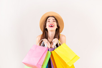 Spring summer season sale concept. Attractive young woman with long brunette hair, wearing sexy yellow dress, holding many different blank shopping bags over white background. Copy space, close up.