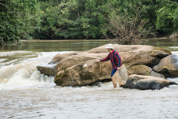 The man catching fish at the waterfall