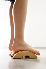 Masaż stóp. Stopy  dziecka podczas masażu urządzeniem do masażu stóp  na tle drewnianej podłogi. - obrazy, fototapety, plakaty