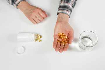 Man hand holds yellow medication capsules of omega 3