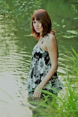 Charming girl bathes in a pond. Beautiful girl in the river near the forest. Young beauty in the water in the hot summer. Sexy brown hair relaxes near the river. Mysterious Amazon.